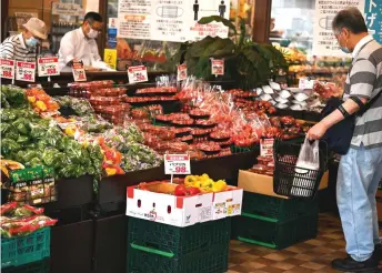  ?? — AFP file photo ?? A man looking at vegetables at a supermarke­t in Tokyo.