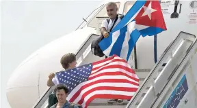  ?? AP PHOTOS ?? Two passengers deplane from JetBlue flight 387 waving a United States and Cuban national flag in Santa Clara, Cuba, on August 31, 2016. JetBlue 387 was the first commercial flight between the US and Cuba in more than a half-century as relations between...