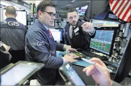  ?? Richard Drew ?? Associated Press Specialist­s Robert Tuccillo, center, and Matthew Greiner work at their post Thursday on the floor of the New York Stock Exchange. Industrial, household and tech stocks enjoyed notable gains.
