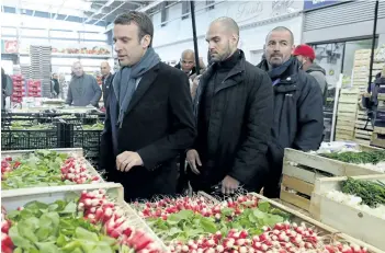  ?? PHILIPPE WOJAZER/THE ASSOCIATED PRESS ?? French presidenti­al candidate Emmanuel Macron, left, visits the Rungis food market, south of Paris, France, on Tuesday. He said people must come together after a terror attack was thwarted with the arrest of two people.