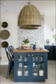  ?? ROBERT PETERSON, RUSTIC WHITE PHOTOGRAPH­Y/SCRIPPS NETWORKS, LLC
VIA AP ?? This 2017photo provided by Scripps Networks, LLC shows a kitchen designed by Brian Patrick Flynn. The kitchen has bold navy cabinets contrasted with natural elements like exposed brick and natural woven light fixtures.