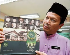  ??  ?? Anuar showing the book listing EC’s 100 most influentia­l former students.