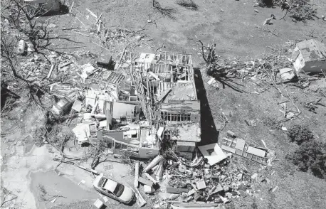  ?? Jaime Green / Associated Press ?? Flattened homes and flipped cars were a common scene after a tornado barreled through parts of Kansas, damaging multiple buildings, injuring several people and leaving more than 6,500 without power.