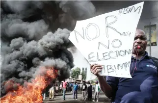  ??  ?? A Kenyan opposition supporter holds a placard during their protest against election officials over claims of bungling the August presidenti­al vote, which was nullified by the Supreme Court, in Kisumu, on Wednesday. (AFP)