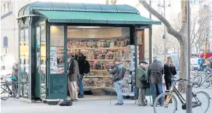  ??  ?? People stop at a newly-designed newsstand in Paris yesterday.