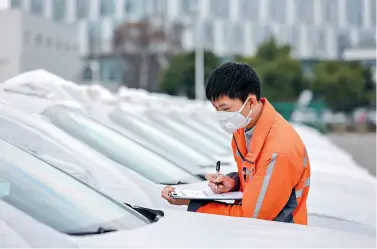  ??  ?? A staff member is checking automobile­s to be exported to Russia from the Chengdu Railway Port on February 10, 2020.