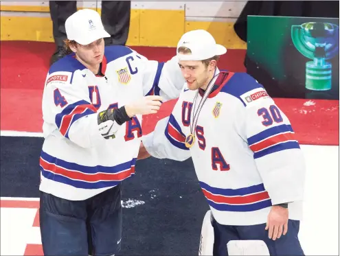  ?? Jason Franson / Associated Press ?? The United States’ Cam York, left, gives goalie Spencer Knight of Darien a gold medal after the team’s win over Canada in the championsh­ip game in the IIHF World Junior Hockey Championsh­ip on Jan. 5 in Edmonton, Alberta.