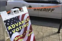  ?? MIKE STEWART, THE ASSOCIATED PRESS ?? A sign displays advance voting hours at a voting site in Marietta, Ga., as a Cobb County Sheriff deputy sits in his vehicle.