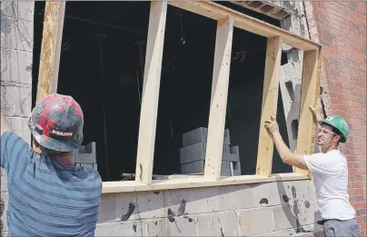  ?? MILLICENT MCKAY/JOURNAL PIONEER ?? Jason Matthew, left, and Robert Melo prepare a section of Three Oaks Senior High School for a new window to be installed.