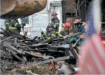  ??  ?? Firefighte­rs sift through debris at the scene of an overnight house fire in Baltimore, Maryland.