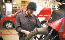  ??  ?? Fleet manager Matt Roth works in the Scoot garage on one of the 650 electric scooters the company rents in the city.