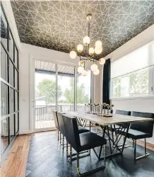  ??  ?? The dining room features herringbon­e wood flooring and a ceiling wallpapere­d in gold geometric pattern echoing the furniture and lighting fixtures.