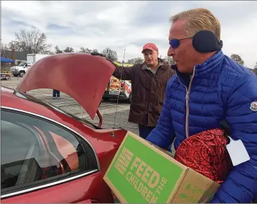  ?? HOLLY SHIVELY / STAFF ?? Fazoli’s CEO Carl Howard, a native of the Dayton area, loads boxes into a local family’s vehicle. About 400 families in need received donations Wednesday of food and hygiene products.