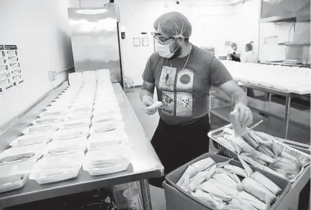  ??  ?? Edson Cerda places tamales into plastic containers at Cocina Compartida de Trabajador­es Cooperativ­istas on June 17.