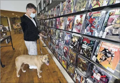  ?? PHOTOS BY JOEL ROSENBAUM — THE REPORTER ?? Jene Alameda and his dog, Hank, from Fairfield, scan the wall of comic books Wednesday at Zeppelin Comics in Benicia. The store is owned by Dan and Natasha Curtis and has been open for five years and carries a wide array of products including individual issue comics, graphic novels, Funko Pop characters, children’s books, a small supply of board games, and their popular store-branded T-shirts.