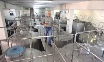  ?? — AFP photos ?? Alaa Mansur, production manager at the Haddad winery, checks on the vats at the Eagle Distilleri­es in Zarqa.