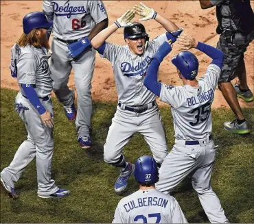  ?? JOHN STARKS / DAILY HERALD ?? Enrique Hernandez (center) celebrates with teammates after hitting a grand slam in the third inning to give the Dodgers a 7-0 lead. The outfielder also homered in the second and ninth innings.