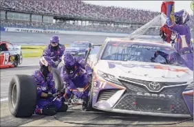  ?? John Bazemore / AP ?? Denny Hamlin’s pit crew works to get him back on the track at Talladega on Sunday. Hamlin’s win puts him into the next round of the playoffs.