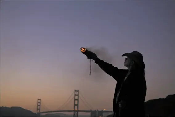  ?? Liz Moughon / The Chronicle 2018 ?? Dana Bark, whose son Donovan jumped off the Golden Gate Bridge in 2008, burns sage at the end of the annual Names in the Sand ritual at Baker Beach in June.