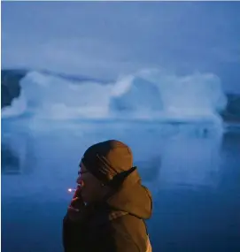  ?? FOTO: FELIPE DANA (DPA) ?? Ein Einheimisc­her raucht in Grönland vor einem Eisberg eine Zigarette. Nicht nur die Eismassen auf Grönland schmelzen bedrohlich schnell.
