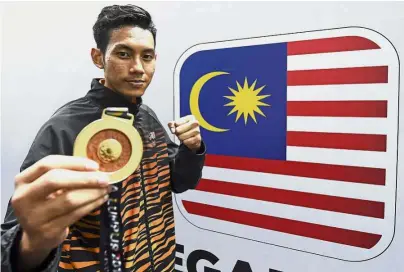  ??  ?? For my country: Malaysia’s taekwondo exponent Rozaimi Rozali posing with his gold medal in front of the Jalur Gemilang after winning the men’s below 68kg category event. — Bernama
