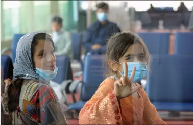  ?? REUTERS ?? Evacuees from Afghanista­n are seen through a glass window as they sit in a hall upon their arrival at Al Maktoum Internatio­nal Airport (DWC) in Dubai, United Arab Emirates, on Thursday.