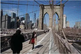  ?? (Associated Press) ?? Tourist Ines Tshiyomba, center, poses as her friend Garethe Mawonso takes her photo March 16 on the Brooklyn Bridge in New York.