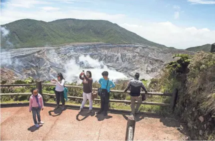  ??  ?? Tourists admire the beauty of Poás Volcano National Park in Costa Rica. The nation leads the Latin American region in health and primary education. It also provides universal health care to citizens. EZEQUIEL BECERRA/AFP/GETTY IMAGES FILE PHOTO