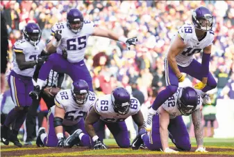  ?? Patrick McDermott / Getty IMages ?? Wide receiver Adam Thielen (19) leaps over his kneeling Vikings teammates to celebrate his touchdown. Thielen was one of five Minnesota players to find the end zone.