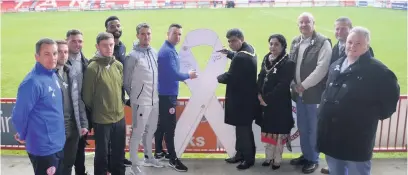  ??  ?? Accrington Stanley’s management team and playing squad along with local Councillor­s sign the large promotion ribbon to mark the start of the White Ribbon campaign.