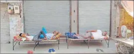  ?? SAMEER SEHGAL /HT ?? Workers rest outside closed shops during the weekend lockdown in Amritsar on Sunday.