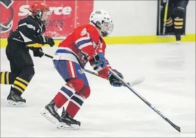  ?? JASON SIMMONDS/TC MEDIA ?? Sid McNeill of the Summerside Capitals carries the puck while being pursued by the Western Warriors’ Mason Delaney during the opening game of the 19th annual Edd McNeill Memorial hockey tournament at The Plex in Slemon Park on Thursday evening. McNeill...