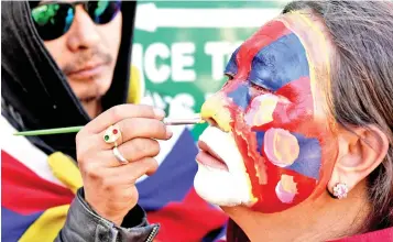  ?? — AFP photo ?? A Tibetan living in exile gets her face painted outside the Dalai Lama’s temple.