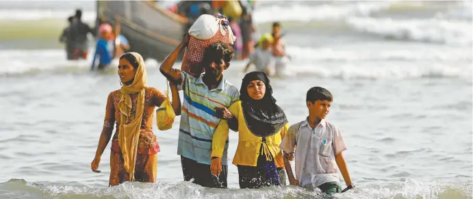  ??  ?? Rohingya refugees walk to shore after crossing the Bangladesh– Myanmar border by boat this week.