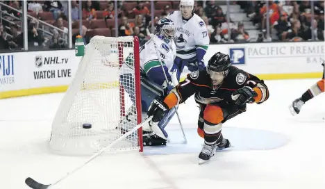  ?? GETTY IMAGES ?? The Ducks’ Andrew Cogliano lunges for the puck as Canucks goalie Ryan Miller looks on. Cogliano scored the first goal in a 4-2 Ducks win.