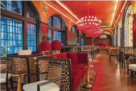  ?? ?? Red crystal chandelier­s cast a glow over the natural fiber-covered furniture in the Founders Bar.