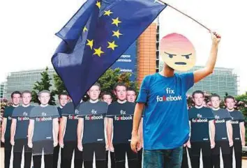  ?? Reuters ?? A protester holds an EU flag next to cardboard cutouts depicting Mark Zuckerberg ahead of a meeting between Zuckerberg and leaders of the European Parliament in Brussels on Monday.