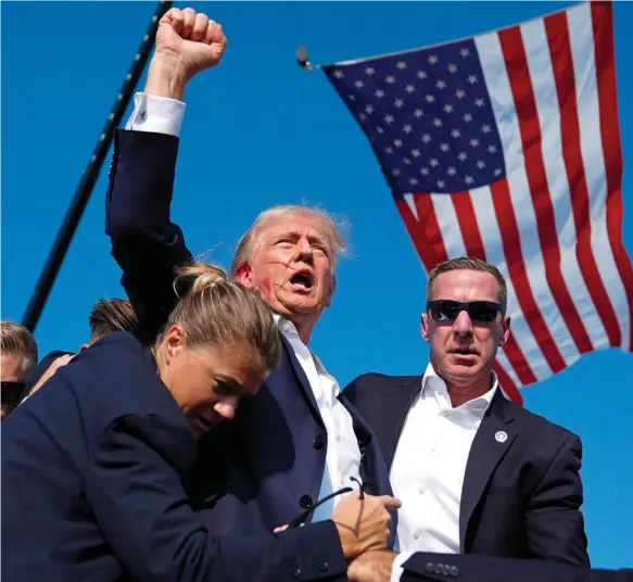  ?? ?? Historic image: Donald Trump seizes the moment to prove his survival and shouts ‘fight, fight, fight’ to the relief of the crowd