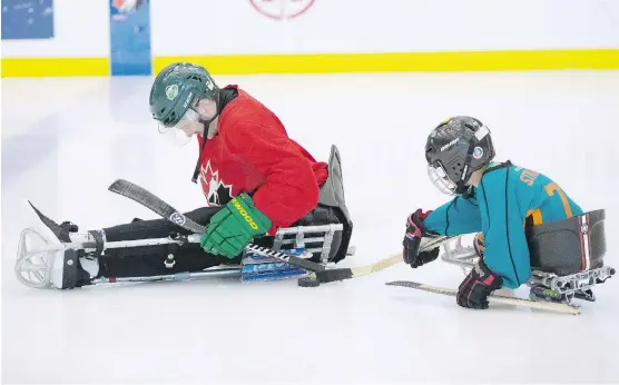  ?? PHOTOS: LEAH HENNEL ?? Humboldt Broncos crash survivor Ryan Straschnit­zki, left, and brother Connor learn the rudiments of sledge hockey at the WinSport Centre in Calgary on Tuesday.