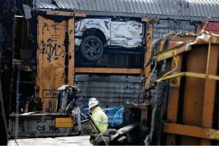  ?? BILL LACKEY PHOTOS / STAFF ?? Work continues on cleanup of the train derailment in Clark County Monday. A worker is shown in the foreground as a load of Ford F-150 trucks is shown in the background.