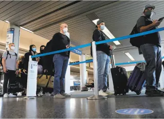  ?? Antonio Perez / Chicago Tribune ?? Travelers line up at O’Hare Internatio­nal Airport in Chicago on March 11. With only about 20% of adults fully vaccinated, officials still urge that travel be limited to essential trips.