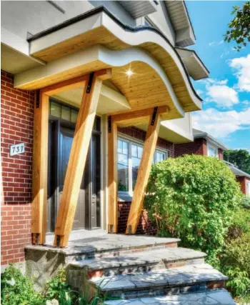  ??  ?? This front porch features a curved staircase and a stunning wavy roof. The bright wood details, the stately red bricks