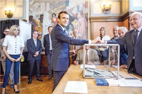  ??  ?? French President Emmanuel Macron casts his ballot next to his wife Brigitte Macron at a polling station in Le Touquet on Sunday. (AFP)