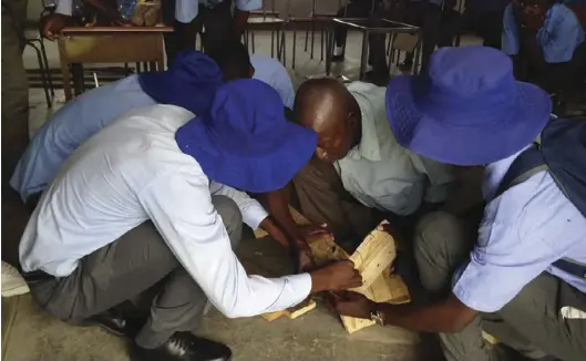  ??  ?? An elderly man teaching Bazha Secondary School pupils how to build a beehive