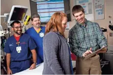  ?? TROYE FOX / UWM ?? UWM student app developer Evan Timmermann shows the First Five Minutes app to physicians Amy Drendel, Danny Thomas (left) and Michael Meyer. They are part of a team that developed the app, which allows ER physicians to quickly calculate dosages for...