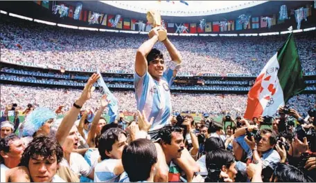  ?? Bob Thomas Getty Images ?? DIEGO MARADONA holds aloft the 1986 World Cup Trophy that the Argentine team captain brought home to his worshiping fans.