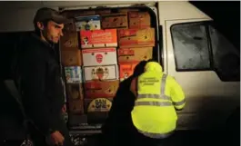  ?? DANIEL MIHAILESCU/AFP/GETTY IMAGES ?? A Romanian customs officer searches a van for smuggled cigarettes and alcohol. Price hikes in western European countries have made traffickin­g highly lucrative.