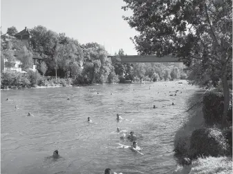  ??  ?? In Bern, Switzerlan­d’s capital, some people commute to work by swimming in the Aare River, their clothing, phones, and wallets secure in a “Bern” dry bag, which they hug like a life jacket.