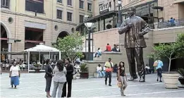 ?? Picture: GALLO IMAGES/ STUART FOX ?? CONTRASTS: Shoppers gather near a large statue of former president Nelson Mandela, installed on Nelson Mandela Square at Sandton City mall in Johannesbu­rg.