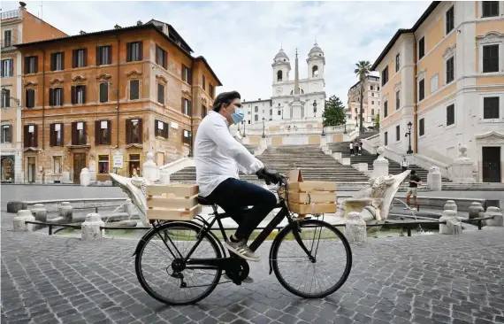  ?? AFP ?? A delivery man rides a bicycle across Piazza di Spagna and the Spanish Steps in central Rome on Monday during the country’s lockdown aimed at curbing the spread of the COVID-19 infection.